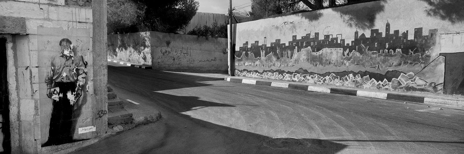 A poster of the Palestinian poet Mahmoud Darwish (left), Aida refugee camp, near Bethlehem, West Bank, 2009; photograph by Josef Koudelka from ‘This Place,’ an exhibition of pictures by twelve photographers of Israel and the West Bank, at the Brooklyn